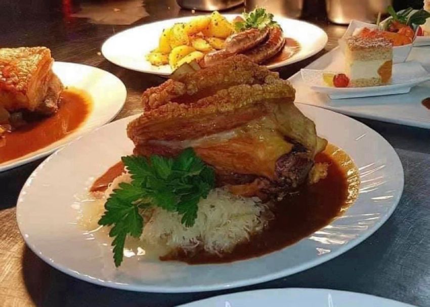 Schweinshaxe mit Sauerkraut und Soße angerichtet auf einem runden Teller